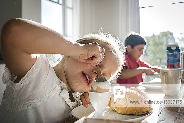 Girl eating a boiled egg at dining table
