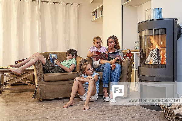 Familie entspannt sich und liest im Wohnzimmer am Kamin