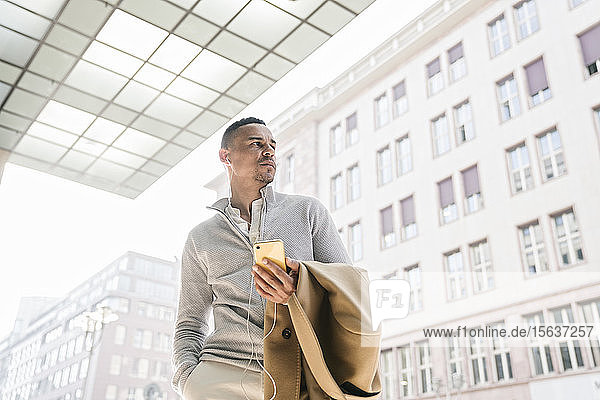 Porträt eines Geschäftsmannes mit Kopfhörer und Smartphone in der Stadt