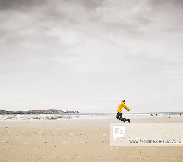 Junge Frau mit gelber Regenjacke am Strand  Bretagne  Frankreich