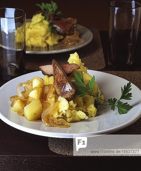 Nahaufnahme von Putenleber mit Kartoffel- und Apfelpüree in Tellern auf dem Tisch serviert