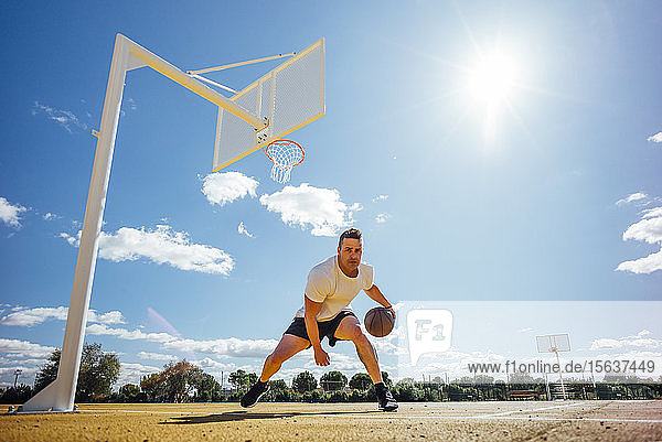 Mann spielt Basketball auf gelbem Platz  dribbelt