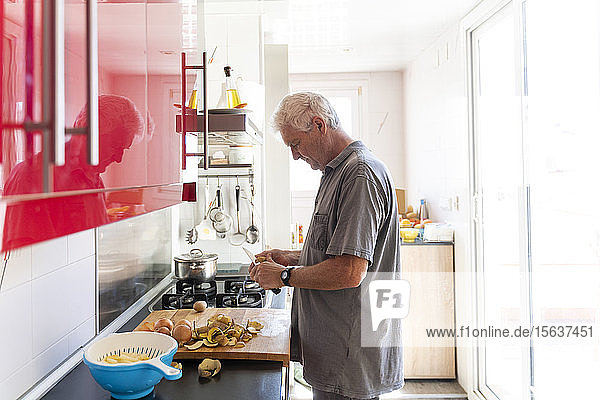 Älterer Mann bereitet in seiner Küche Kartoffeln zu