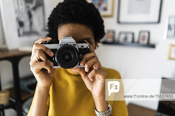Junge Frau  die zu Hause mit einer Oldtimer-Kamera fotografiert