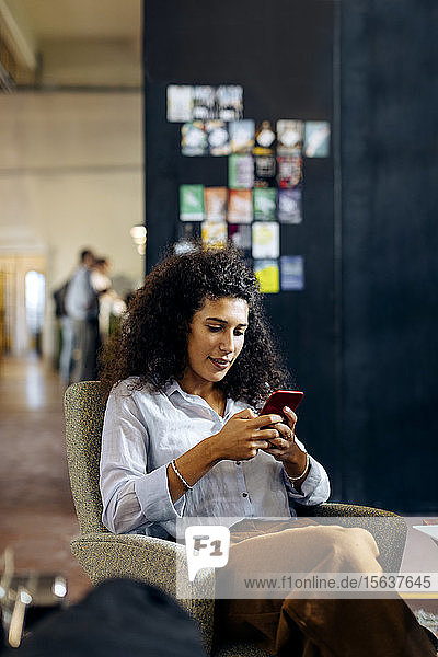 Junge Geschäftsfrau benutzt Smartphone im Loft-Büro