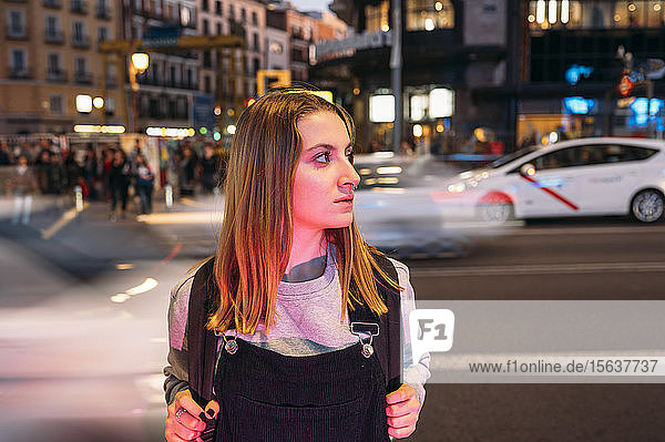 Young woman standing at night in the city on the street