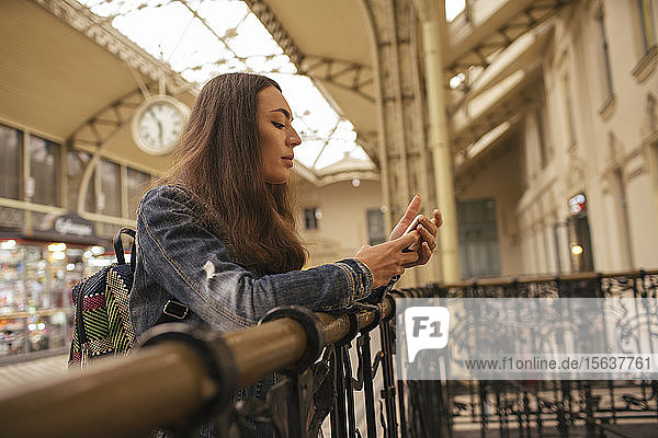 Junge weibliche Reisende mit Smartphone am Bahnhof