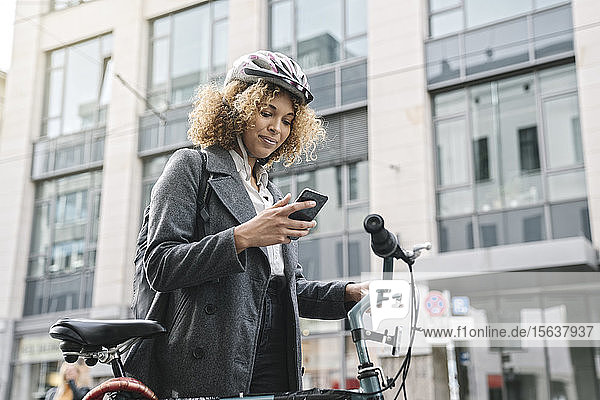 Frau mit Fahrrad und Smartphone in der Stadt  Berlin  Deutschland