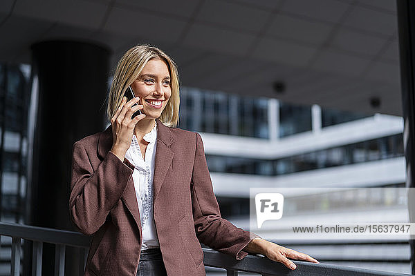 Smiling young businesswoman on the phone in the city