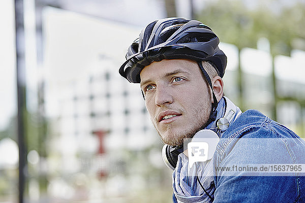 Porträt eines Studenten mit Fahrradhelm und Kopfhörer