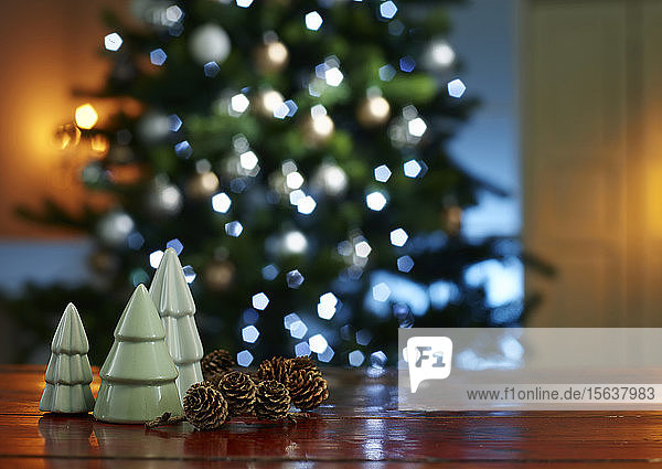 Nahaufnahme von kleinen Weihnachtsbäumen mit Tannenzapfen auf hölzernem Tisch zu Hause