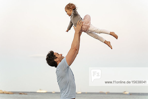 Glücklicher Vater wirft Tochter an den Strand