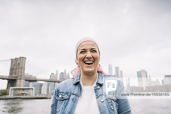 Porträt einer lachenden Frau mit Krebstuch an der Brooklyn Bridge in New York  USA