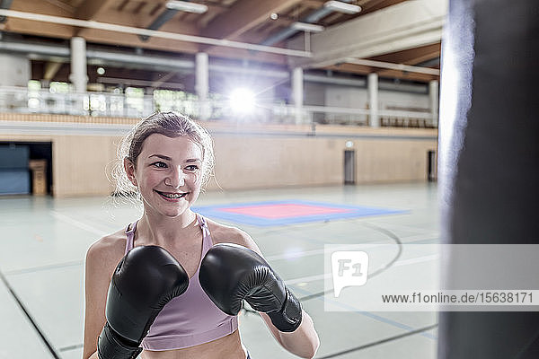 Lächelnde Boxerin beim Boxsacktraining in Sporthalle