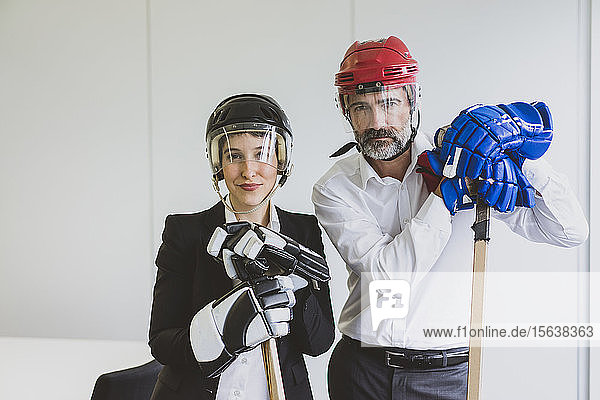Portrait of businesswoman and businessman wearing ice hockey equipment in office