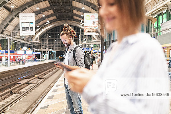 Menschen  die am Bahnhof auf den Zug warten und Smartphones benutzen  Berlin  Deutschland