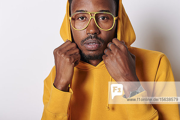Junger Mann mit gelbem Kapuzenpullover und Brille