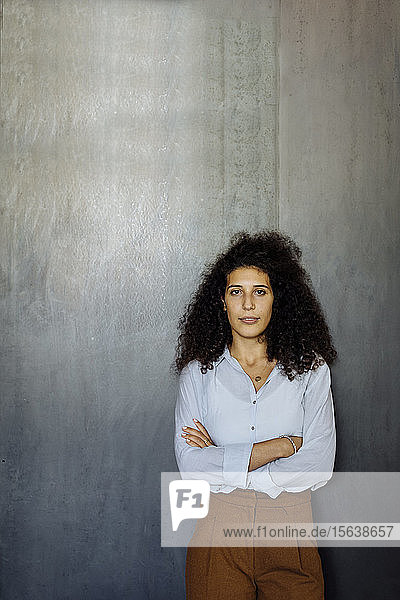 Porträt einer selbstbewussten jungen Geschäftsfrau  die vor einer grauen Wand steht