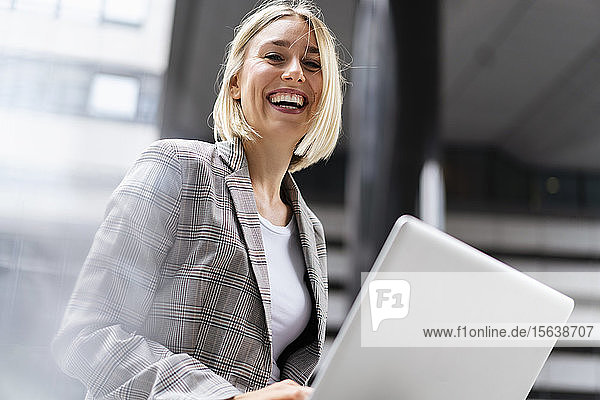 Porträt einer glücklichen jungen Geschäftsfrau mit Laptop in der Stadt