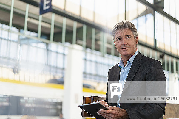 Mature businessman using tablet at station platform