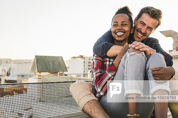 Glückliches  liebevolles junges Paar sitzt abends auf dem Dach