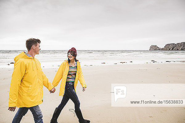 Young woman wearing yellow rain jackets and walking along the beach  Bretagne  France