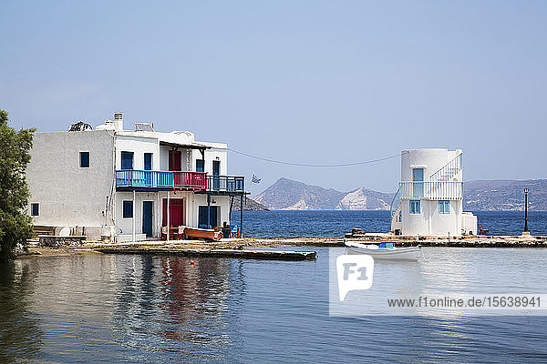 Das Dorf Embourios mit einem Wohnhaus am Wasser und einem kleinen Boot  das am Kai vertäut ist; Embourios  Insel Milos  Kykladen  Griechenland