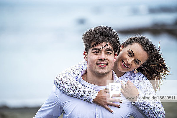 Porträt eines jungen Paares mit vom Wind zerzausten Haaren am Strand; Wellington  Nordinsel  Neuseeland