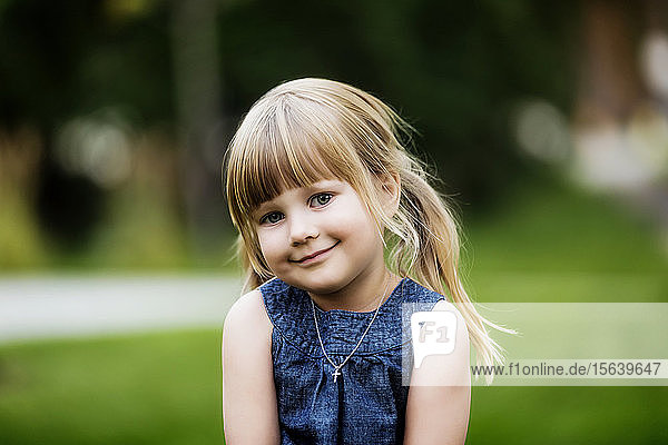 Porträt eines niedlichen jungen Mädchens mit blondem Haar in Zöpfen und einer Halskette mit einem Kreuzanhänger; Edmonton  Alberta  Kanada