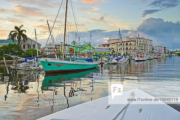 Colourful waterfront of Belize City at dusk with reflections in the tranquil water; Belize City  Belize District  Belize