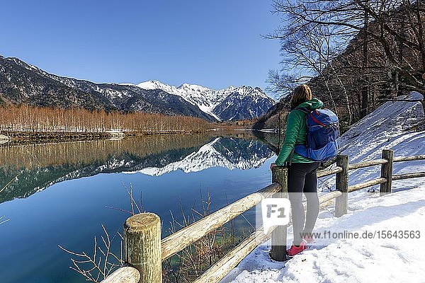 Junge Frau schaut auf das Meer  die japanischen Alpen spiegeln sich im Taisho-Teich  im Hintergrund der Berg Hotaka  Kamikochi  Matsumoto  Nagano