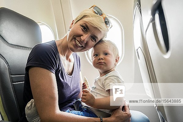 Mother with baby playing in a passenger airplane  Poland  Europe