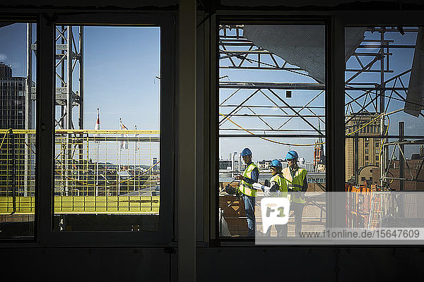 Männliche und weibliche Architekten durch Fenster auf der Baustelle gesehen