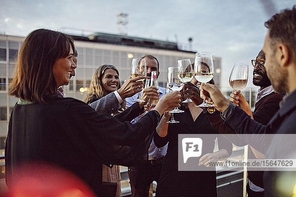 Business coworkers toasting wineglasses while celebrating in office party on terrace