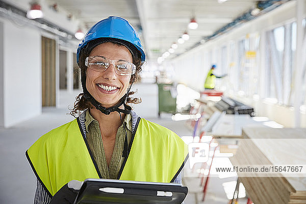 Porträt einer lächelnden Vorarbeiterin mit digitalem Tablett auf der Baustelle
