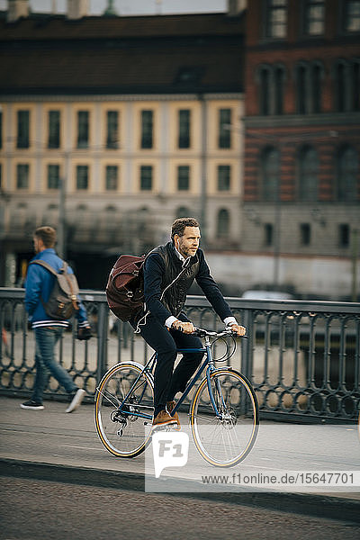 Fahrrad fahrender Geschäftsmann in voller Länge auf der Brücke