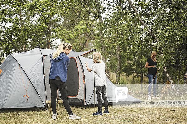 Geschwister bereiten Zelt im Wald auf dem Campingplatz vor