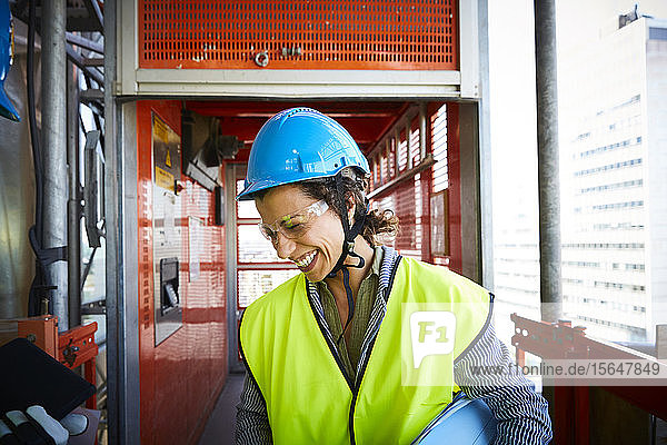 Lächelnde Ingenieurin in reflektierender Kleidung auf der Baustelle