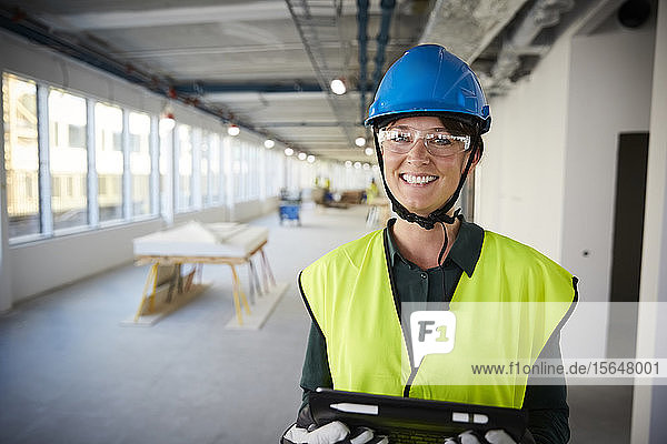 Porträt einer lächelnden Ingenieurin in Arbeitsschutzkleidung auf einer Baustelle