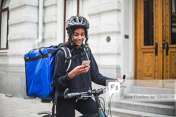 Food delivery woman using smart phone in city