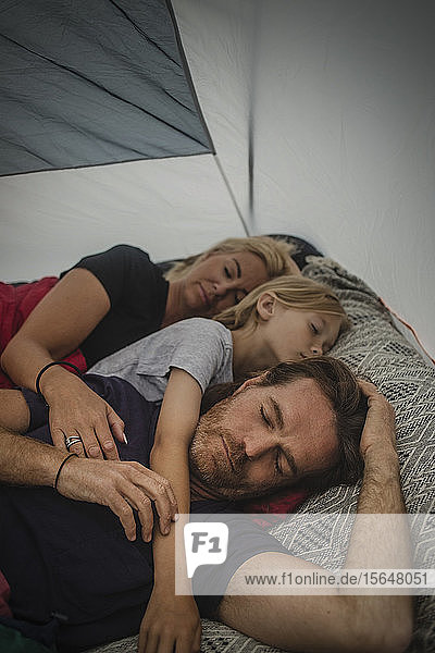 Family sleeping with closed eyes in tent during camping