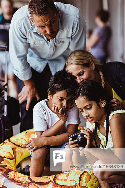 Mädchen zeigt der Familie eine Kamera  während sie am Bahnsteig des Bahnhofs wartet