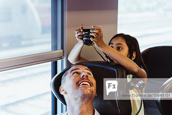 Mädchen fotografiert Vater mit Kamera  während sie im Zug sitzt