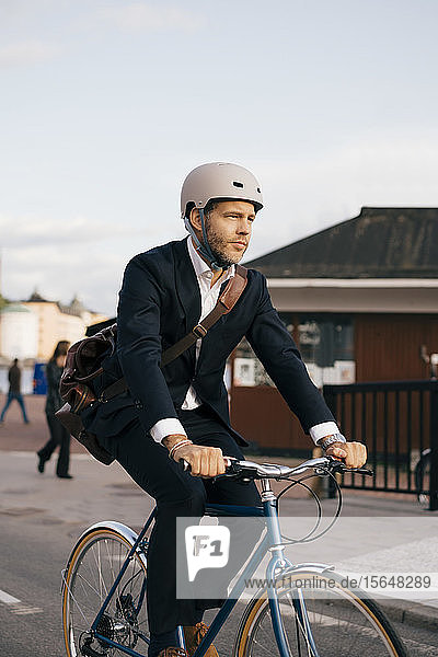 Selbstbewusster Geschäftsmann fährt Fahrrad auf der Straße in der Stadt