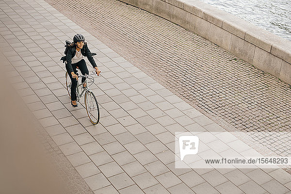 Hochwinkelansicht einer Geschäftsfrau  die auf einem Fußweg Fahrrad fährt