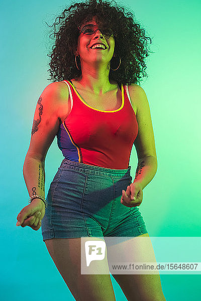Young woman in red tank top dancing against turquoise background