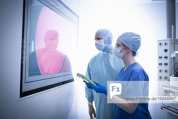 Nurse and surgeon inspecting screens in operating theatre in hospital setting