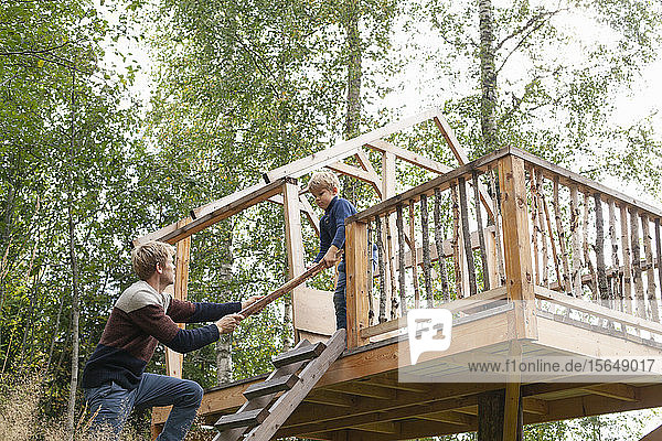 Vater und Sohn bauen gemeinsam Baumhaus im Garten