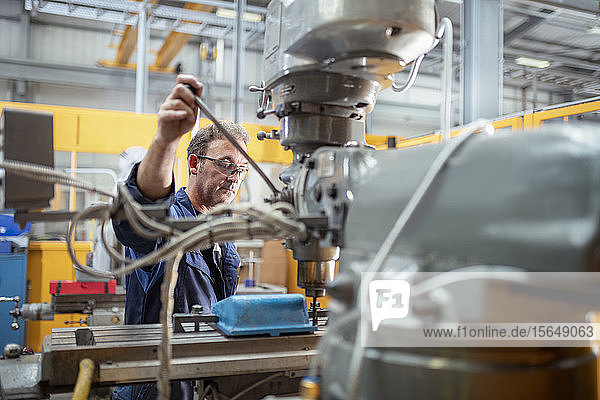 Engineer operating lathe in electrical engineering factory