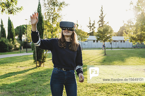 Junge Frau schaut durch VR-Headset im Park